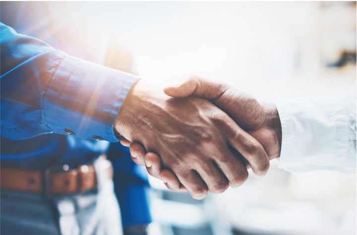 Two men shaking hands. A white bloom blurs out the background.