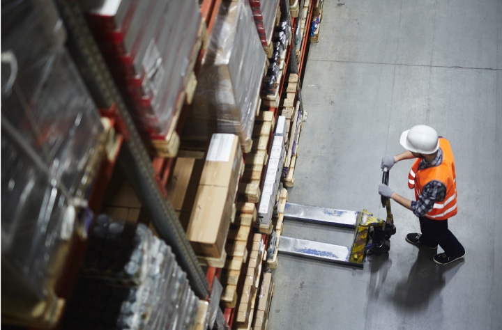 A person picking up boxes in a warehouse.